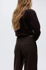 Pantalón sastrero de corte amplio con pinzas, cierre frontal con botón y corchete ocultos, bolsillos laterales al bies y bolsillos decorativos traseros.