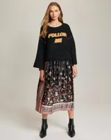 Sweater negro con cuello redondo y mangas largas acampanadas. Tiene la inscripción "Follow Me" en color naranja en el frente.