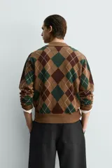 Polo de punto de corte relajado, con estampado de rombos en tonos marrón y verde. Presenta cuello solapa con abertura frontal, manga larga y acabados en rib.