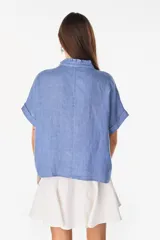 Camisa de lino marrón con mangas cortas, cuello mao con volados, cierre frontal con botones blancos y detalles de calados verticales en el frente.