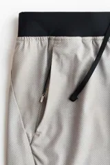 Short deportivo de tejido funcional con tecnología DryMove para absorción de sudor. Presenta cintura elástica con cordón oculto, bolsillos laterales al bies, aberturas en el bajo y detalles reflectantes.