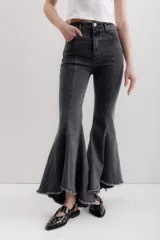 Pantalón de jean elastizado color gris oscuro, con diseño de campana y volados en la parte baja de la pierna. Presenta un ruedo descosido con un juego de largos, siendo más largo en la parte trasera.