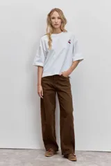 Remera blanca de corte oversize con cuello redondo y mangas cortas, presenta un pequeño bordado de cerezas en el pecho.