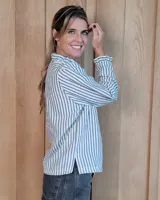 Camisa de manga larga con estampado de rayas verticales en tonos crudo y beige. Presenta cuello alto con volados, cierre frontal con botones dobles y puños con volados.