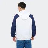 Campera deportiva Umbro del Club Nacional de Football modelo Venti, con capucha y cierre frontal completo. Diseño en color blanco con mangas azules, puños elásticos y detalles en rojo. Incluye el logo de Umbro y el escudo del club bordados en el pecho.