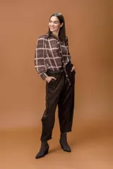 Camisa de manga larga con estampado de cuadros, cuello con lazo integrado y cierre frontal abotonado. Presenta un diseño fluido y elegante.