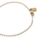 Pulsera de cadena fina con eslabones ovalados bañada en oro de 18k, con cierre de mosquetón y pequeña placa con logotipo colgante.