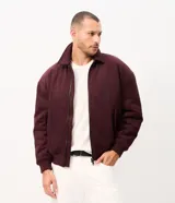 Campera bomber Marfinno para hombre, de gamuza sintética (suede) color tostado, con cuello camisero, cierre frontal metálico, bolsillos frontales y terminaciones en rib en puños y ruedo.