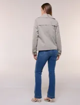 Gabardina corta gris, de silueta ligeramente entallada con diseño clásico de trench, cuello camisero con solapas amplias, cierre cruzado con doble botonadura y bolsillos laterales diagonales.
