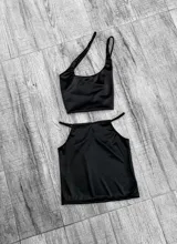 Top negro asimétrico con un solo tirante ancho y un corte en el pecho.