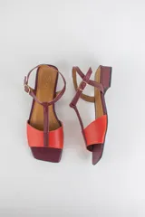Sandalias de cuero combinadas en negro y marfil, con diseño de tiras en T, taco cuadrado bajo y pulsera con hebilla ajustable al tobillo.