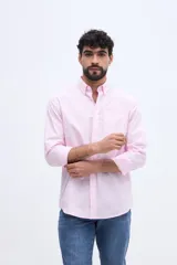 Camisa de manga larga color rosado, con cuello abotonado, cierre frontal de botones y un bolsillo ojal en el pecho.