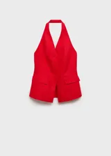 Chaleco rojo de lino con cuello halter, sin mangas, corte entallado, cierre frontal con botones y dos bolsillos de solapa laterales.