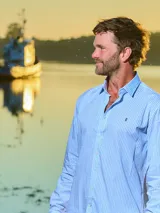 Camisa de vestir de hombre a cuadros celestes y blancos, de corte clásico, con cuello italiano y logo bordado en el frente.