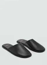 Mules de cuero caprino color negro, con punta triangular y diseño destalonado.