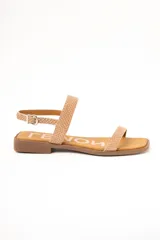 Sandalias planas de cuero color beige con estampado tipo animal print de serpiente texturado. Posee una tira delgada en la parte delantera y una tira ajustable con hebilla metálica alrededor del tobillo, sobre una suela plana y punta cuadrada.