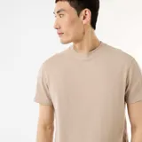 Camiseta de cuello redondo y manga corta color beige, con textura de nido de abeja y pequeña etiqueta decorativa en el borde inferior.