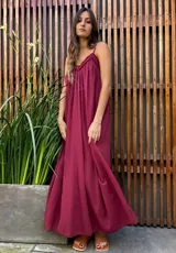 Vestido largo tipo solera color bordó, con breteles finos y escote con detalle de frunces y terminación en puntilla. Presenta un corte holgado y fluido.