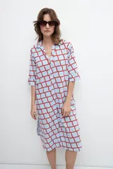 Maxi vestido camisero celeste con estampado geométrico de cuadrados rojos, mangas cortas y aberturas laterales.