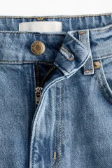 Jean de tiro alto con corte wide leg y piernas amplias. Confeccionado en denim de algodón con leve stretch, presenta diseño de cinco bolsillos, cierre con botón y bajo con detalle de ruedo desgastado.