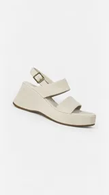 Sandalias de plataforma con cuña forrada en gamuza beige, tiras anchas en el empeine y tira ajustable en el talón con hebilla metálica.