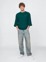 Remera de corte oversized en color beige claro, con cuello redondo y mangas de largo medio. Presenta un pequeño bordado del oso Brannan de Gap en el lado izquierdo del pecho.