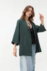 Blazer negro de corte recto y holgado, con doble botonadura frontal, solapas clásicas y mangas tres cuartos con costuras pespunteadas en contraste.