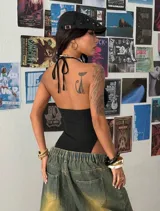 Body negro con escote halter, cordones cruzados al frente con ojalillos metálicos y diseño cavado.
