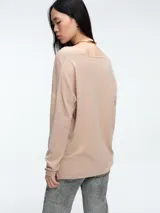 Sweater de punto gris con escote en V profundo, hombros caídos y mangas largas. Presenta un diseño de calce relajado con sutiles micro lentejuelas integradas en el tejido.