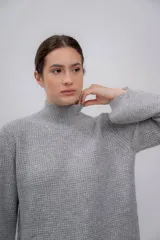 Polera gris de tejido de punto grueso, con cuello alto y mangas largas.