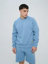 Buzo de felpa bordó, estilo relaxed, con cuello redondo y mangas raglán. Presenta puños y dobladillo acanalados, y una pequeña etiqueta con el logo de Umbro en el lateral inferior.