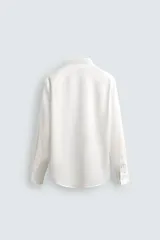 Camisa de corte relajado confeccionada en tejido fluido de lyocell. Presenta cuello solapa, manga larga con puños abotonados y cierre frontal con botones.