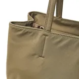 Cartera tipo tote de tela color verde oliva, con doble asa de hombro y detalle de borla decorativa con cordones en uno de los laterales. Incluye un aplique circular metálico con el logo de la marca en la parte frontal.