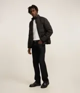 Campera acolchada tipo puffer, color marrón topo, con cuello alto y cierre frontal de cremallera. Presenta costuras horizontales que crean un efecto acolchado.