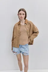 Campera de gabardina tostada, con cuello camisero de pana marrón, cierre frontal de botones metálicos y bolsillos delanteros aplicados con solapa.