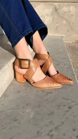 Zapatos de tacón ancho color camel con textura símil serpiente, punta fina y tiras cruzadas con hebilla metálica grande en el lateral.