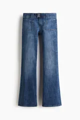 Jeans de denim azul de tiro bajo con leve elasticidad. Presentan un corte ajustado hasta el muslo y acampanado desde la rodilla. El cierre es frontal con botones en una pretina prolongada y cuenta con bolsillos delanteros de parche y bolsillos traseros.