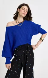 Sweater de punto color azul eléctrico con diseño de hombro caído y escote asimétrico. Presenta textura acanalada, mangas largas con ligero volumen y puños ajustados de canalé.