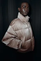Anorak acolchado de efecto brillante con tejido cortavientos y repelente al agua. Presenta cuello subido, cierre frontal con cremallera, bolsillos delanteros con forro polar y cierre de cremallera, y mangas largas con puños elásticos. El bajo es ajustable con cordones elásticos laterales.