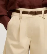 Short de mujer color beige claro, de cintura alta y corte holgado, con pliegues frontales y cierre tradicional. Incluye un cinturón fino de material sintético marrón.