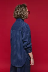 Camisa de manga larga con diseño de rayas verticales y horizontales en color marrón. Presenta un corte oversize con hombros caídos, cuello clásico y cierre frontal con botones.