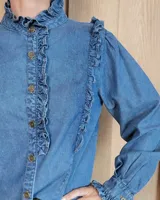 Camisa de denim negro con cuello alto, cierre frontal de botones y detalles de volados en el frente y puños.