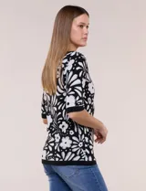 Buzo tejido de punto fino negro con diseño de flores blancas a contraste, escote redondo y mangas de largo al codo.
