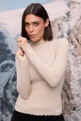 Polera de tejido de punto fino en color beige, con cuello alto, mangas largas y terminaciones con detalle de borde ondulado (ruloté).