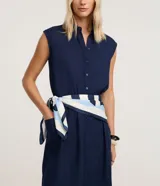 Vestido chemise midi azul marino de Marfinno, confeccionado en mezcla de lino y viscosa. Presenta cierre frontal de botones, cuello camisero, sin mangas y bolsillos laterales.