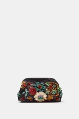 Bolso de mano negro con cuerpo cubierto de abalorios y apliques florales multicolores. Asa de anillas metálicas extraíble en forma de bandolera. Bolsillo interior y forro interior. Cierre mediante clip.