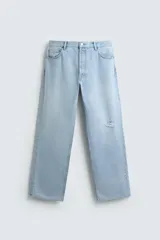 Jeans de denim de algodón, tiro medio, color celeste claro lavado. Corte recto y holgado desde la cadera hasta el tobillo, con rotura en una de las perneras. Presenta cierre frontal con cremallera y botón, y cinco bolsillos.