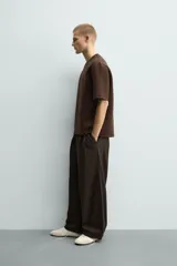 Sudadera de manga corta con corte relajado, confeccionada en tejido técnico compacto de algodón con elasticidad. Presenta cuello redondo y detalle de tacha metálica en la espalda.