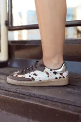 Championes de diseño artesanal con paneles de cuero vacuno con pelo estampado tipo animal print y detalles en cuero liso marrón. Presenta una pieza metalizada en el talón y suela de goma color caramelo.