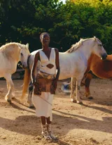 Falda corta de cuero marrón con efecto desgastado o estampado, estilo western, con múltiples bolsillos frontales tipo cargo y un cinturón ancho con hebilla decorativa. Presenta detalles de costura o tachas en el ruedo.